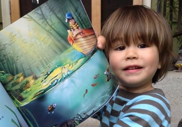 a young boy is holding a book in his hands
