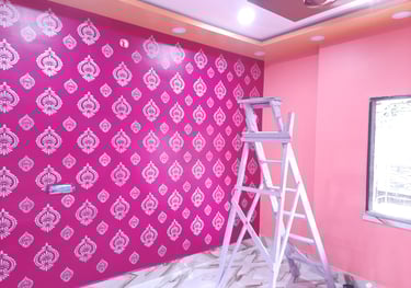 A pink bedroom wall with white stencil pattern art and a wooden step ladder for home painting.