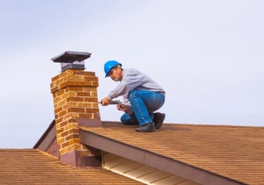 a man in a blue hat and blue jeans is fixing a chimney