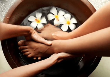 Someone's feet in a bowl of water getting a foot massage.