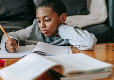 a young boy is sitting at a table with a pencil and pencil