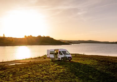 a van parked on a grassy field near a body of water