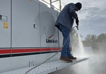 a man in a blue jacket is using a hose to clean a boat