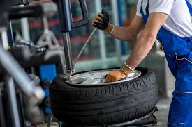a man in a blue overalls and a white shirt is working on a tire