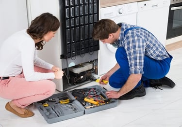 technician repairing a fridge while customer is watching him