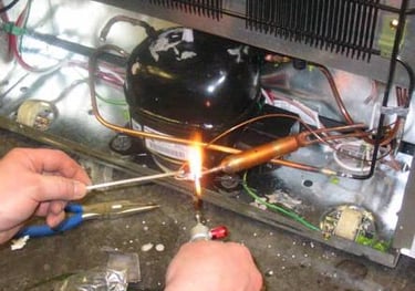 a person soldering a dryer to a compressor