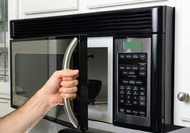 a person opening a black otr microwave door
