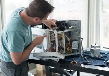 a person repairing a microwave on a table