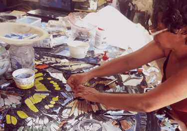 a woman is designing a mosaic tile
