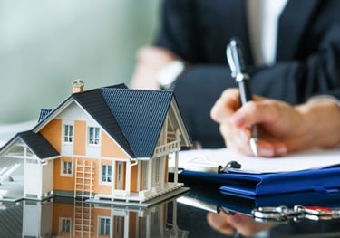 a person sitting at a desk with a pen and house on the table