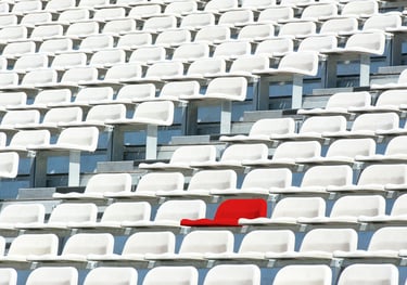 a red chair in a stadium with many white chair