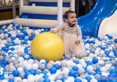 a baby girl in a ball pit with a ball in the middle of a ball