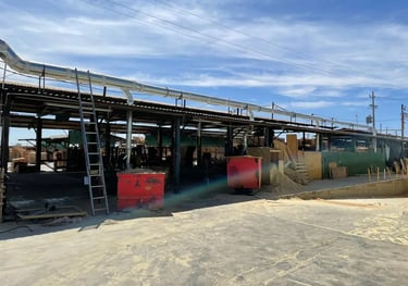 Patio industrial maderero con ductos plateados de un sistema de transporte neumático