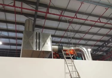 Técnicos de HVAC instalando una caja de filtrado de acero galvanizado en una maquiladora