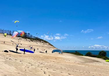 Plusieurs personnes s'entraînent à gonfler leurs parapentes sur la plage. 