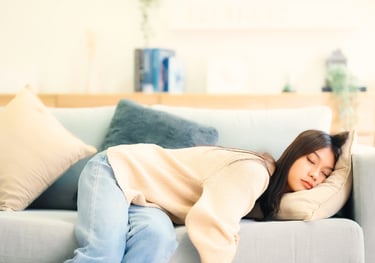 Woman resting on a sofa looking emotionally exhausted, representing stress, overwhelm, fatigue.