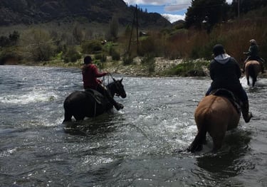 People on horseback riding through a river.