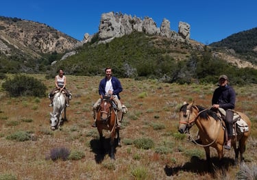 People on horseback riding in a mountainous landscape.