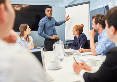 a man in a suit and tie is standing in front of a white boardroom