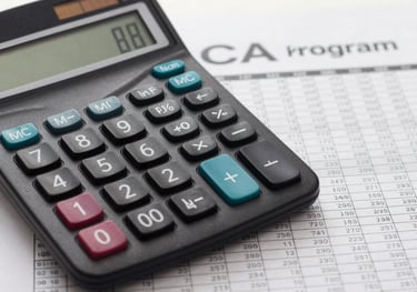A close-up photograph of a calculator and a financial ledger on a Soft White desk, symbolizing the precision of the Commerce and CA program.