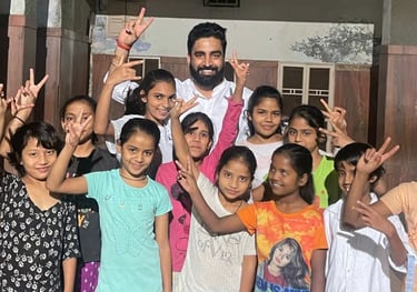 Vikash Sharma with a group of cheerful young girls making peace signs at a school or community center