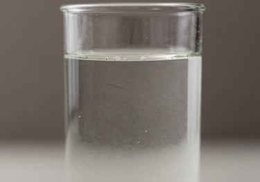 Macro shot of a high-quality liquid cattle supplement in a transparent glass container, showing its purity. Elements of #4B6F63 in the background.