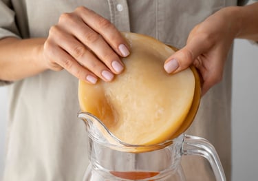 Una persona colocando un cultivo iniciador de SCOBY fresco en una jarra de vidrio.