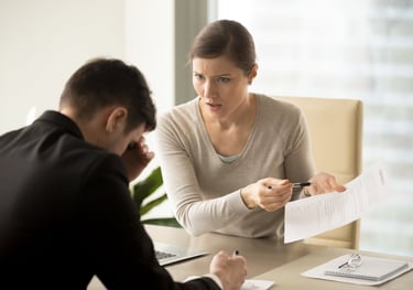 a man and woman sitting at a table with papers