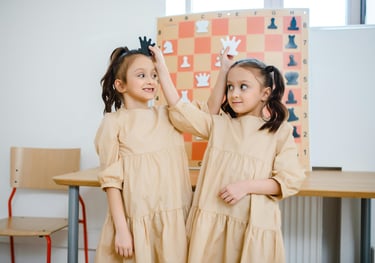 two young girls standing in front of a chess board