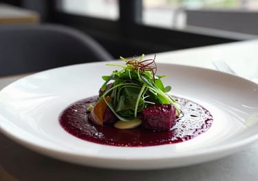 A beautifully plated dish in a minimalist restaurant, featuring deep ripe crimson sauces and fresh greens, shot in natural daylight with a professional food photography style.