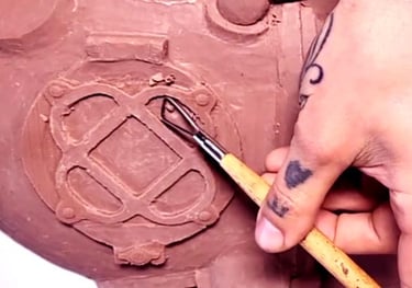 Close up of a hand holding a sculpting tool, carving a Mark 5 diving helmet out of clay.  This sculpture was a commission. 