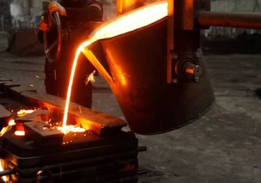 Stock image of a foundry - A pot of glowing melted bronze being poured into a mold.