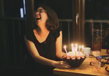 une femme rit aux éclats devant son gateau d'anniversaire, par zohra Elmes