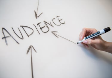 Woman's hand writing the word "audience" on a whiteboard, with arrows. - Swrill