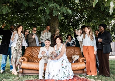 Un couple de mariés sur un canapés entourés de leurs invités