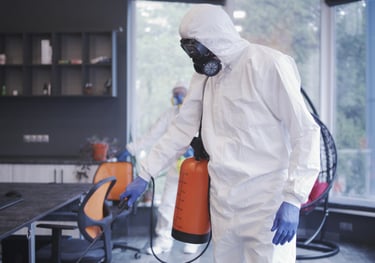 a man in a white hazmat suit and a canister with disinfectant