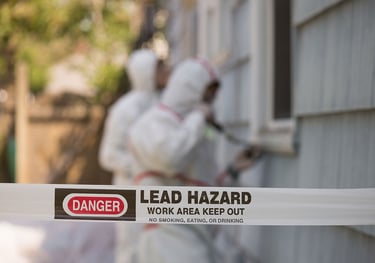 a group of people in white suits with a sign that warns about lead 