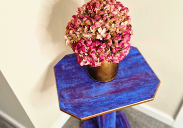 A bright plant or lamp stand painted in a boho style with gold edging