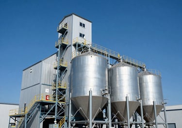 A wide-angle shot of a high-tech grain elevator and processing facility under a clear blue sky, showing the scale and modern innovation of the agricultural industry.