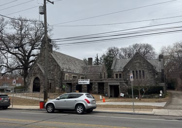 Picture of church building including slight street view with two parked cars.