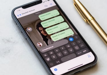 A close-up of a modern smartphone showing a professional messaging interface, sitting on a clean white marble table next to a gold pen, South Asian / Pakistani context, bright natural lighting.