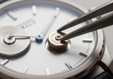 A macro photograph focusing on a small silver watch battery being placed into a high-end Swiss watch movement with precision tweezers, clean lighting.