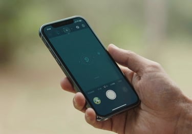 A close-up high-quality photo of a hand holding a modern smartphone in a bright South American / Brazilian outdoor setting. The screen shows a sleek, user-friendly tracking interface with a dark teal color scheme.