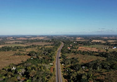An aerial photograph showing a highway winding through a South American / Brazilian landscape under a clear blue sky. The image represents the vast reach and global signal of the tracking service.