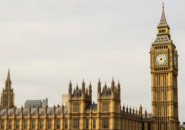 A crisp, professional architectural shot of Big Ben and the Houses of Parliament in London, featuring a soft off-white sky and elegant gold lighting.