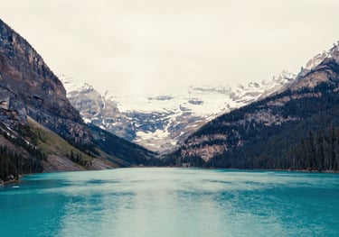 A scenic, high-resolution photo of the Canadian Rockies and a turquoise lake, symbolizing the beauty of relocation, in soft off-white and deep navy blue tones.