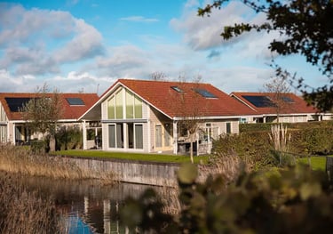  Luxuriöse Ferienhaus in einem Ferienpark direkt am Wasser mit Solaranlage und rotem Ziegeldach.