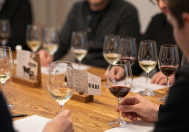 Elegant wine glasses filled with red wine against a minimalist black and burgundy backdrop.