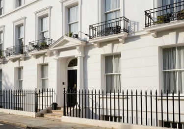 A high-end residential townhouse in a quiet street in Kensington, London. Clean white stucco facade with black iron railings, captured in bright morning light. Elegant Northern European aesthetic.