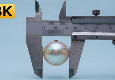 Close-up of a pearl being measured with professional calipers. The focus is on the precision of the shape, with a Soft Pearl Blue background.